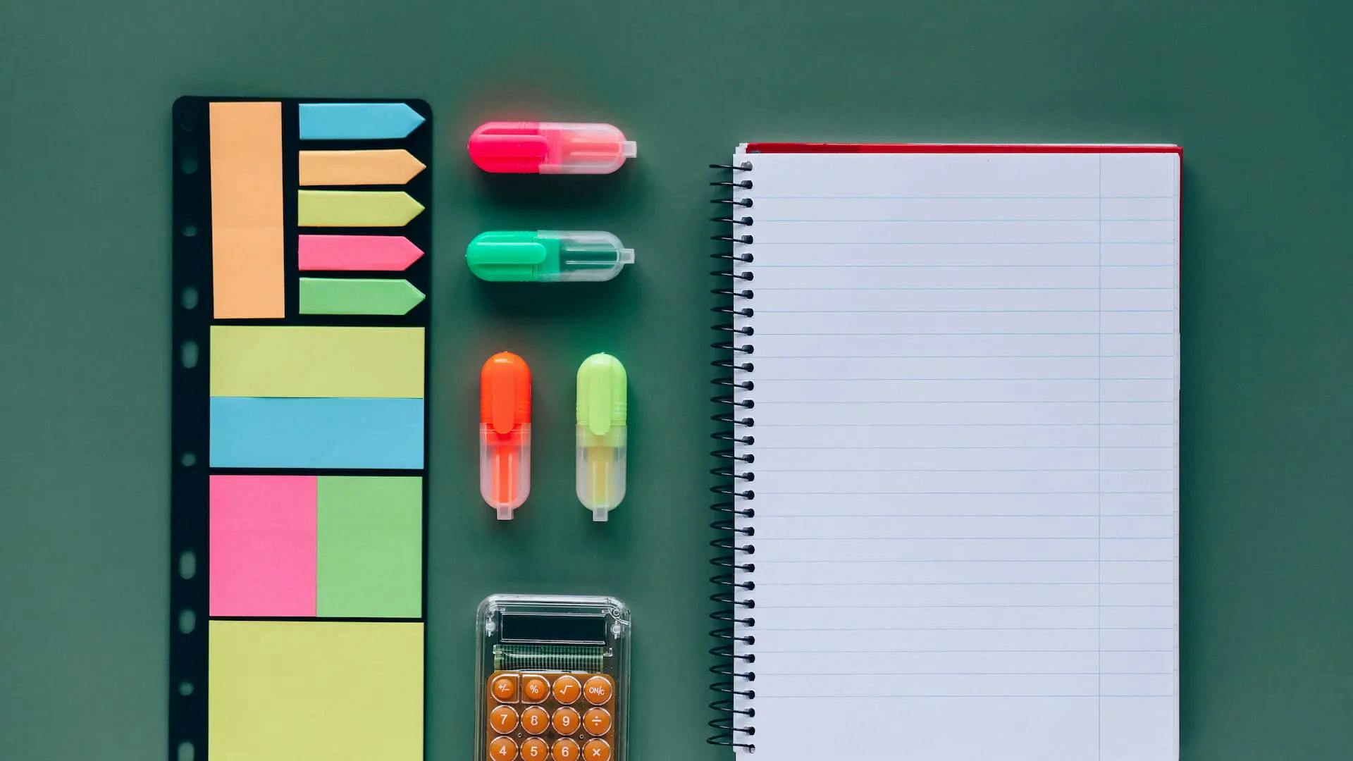 A photo of highlighters, sticky notes, and a notepad on a desk